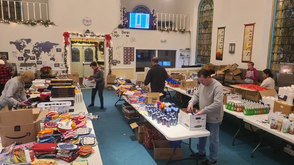 (Volunteers at The First Baptist Church of Mayville carefully pack gifts for Chautauqua County's "Santa for Seniors" program, ensuring each package brings a bit of holiday cheer to older adults in the community.)